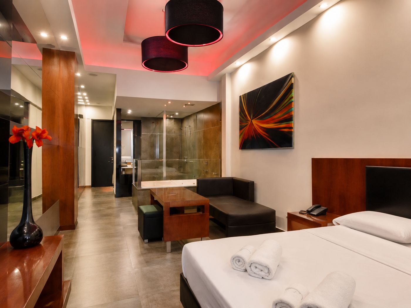 Habitación amplia del Hotel R26 con iluminación LED roja en el cielorraso, hidromasaje y cama king.